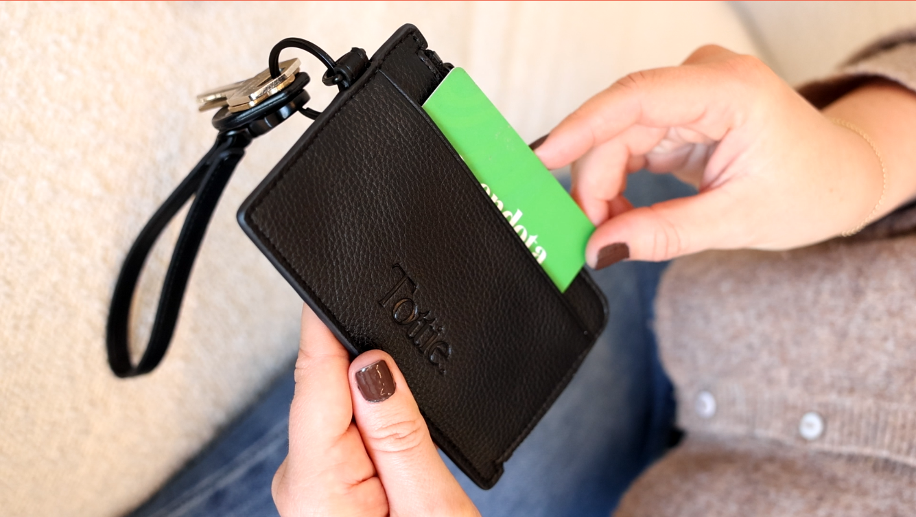 taking a credit card out of a sleek leather cardholder wallet wristlet