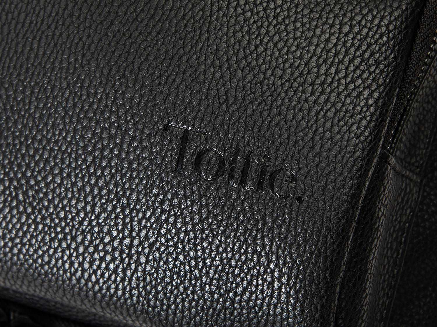 A black leather baby bag backpack with Tottie marking on it