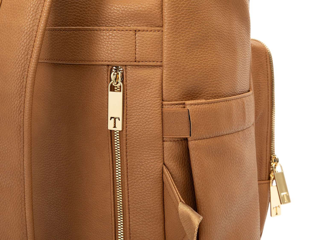 A tan colour leather baby backpack with gold zippers on white background