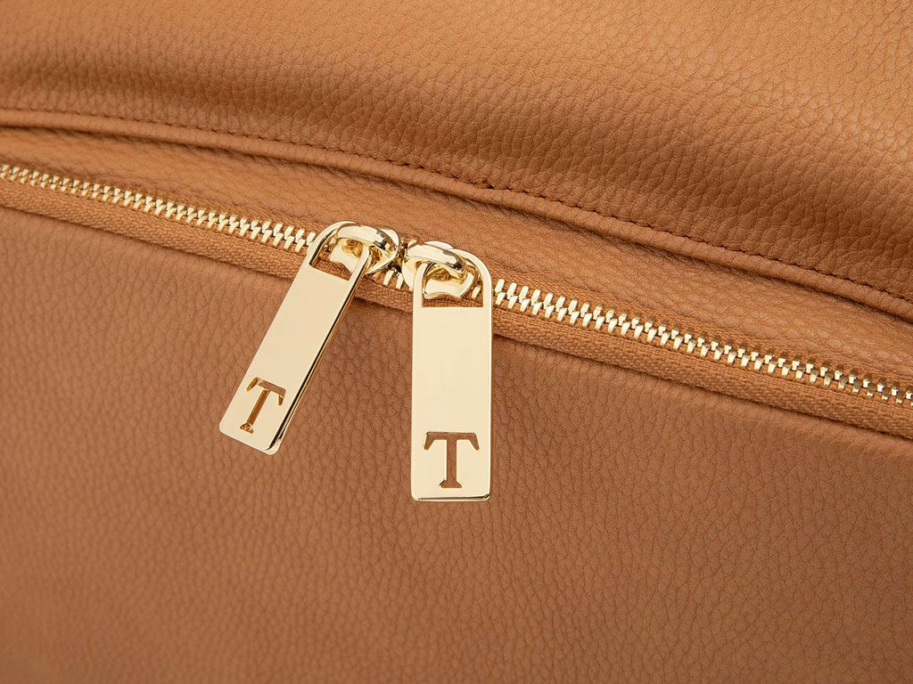 A tan leather baby backpack with gold zippers