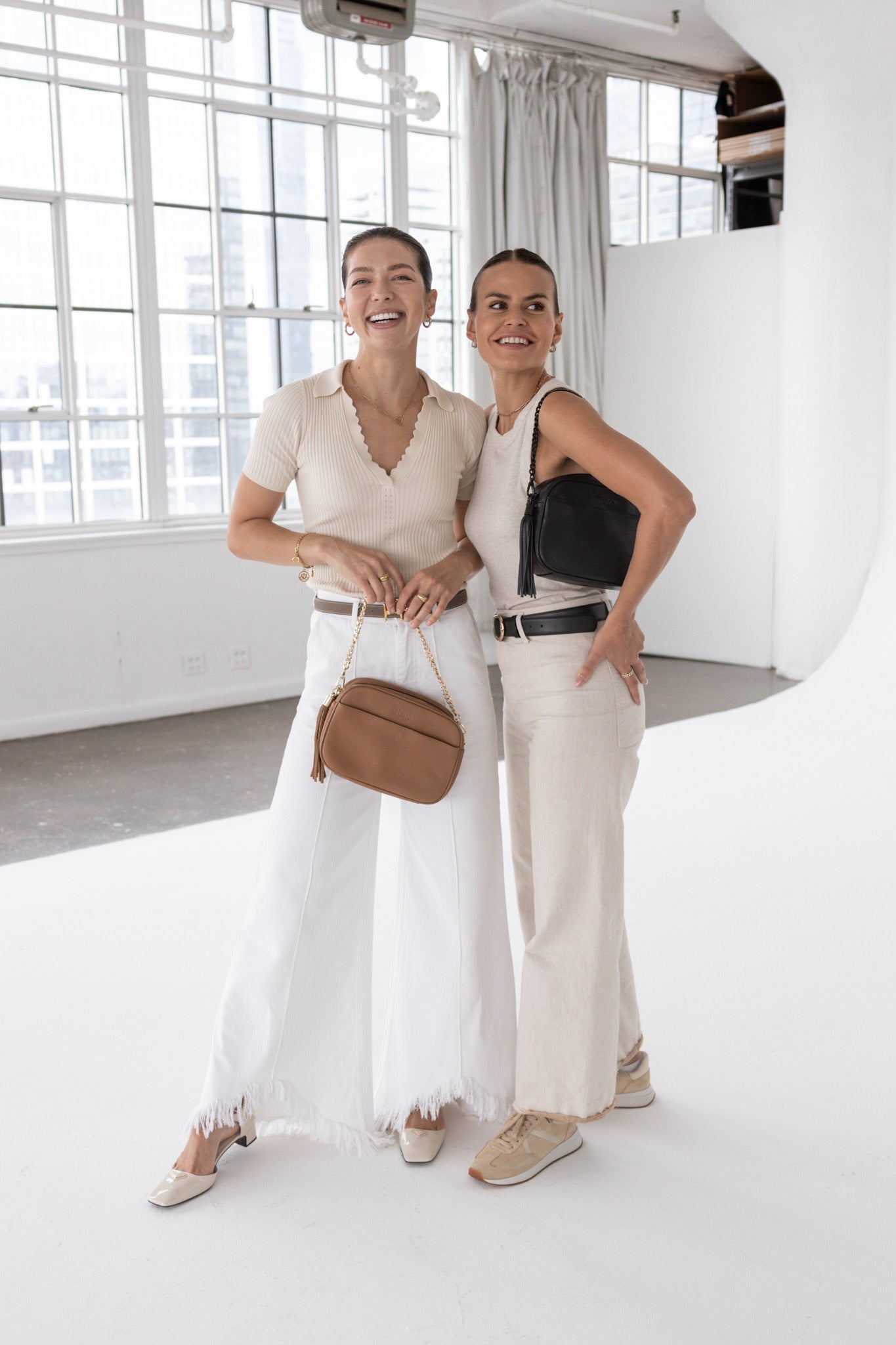 Two women wearing white outfits and carrying tan and crossbody bags from Tottie