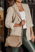 A woman in a blazer standing on the street, carrying a stone Bestie Crossbody Bag from Tottie