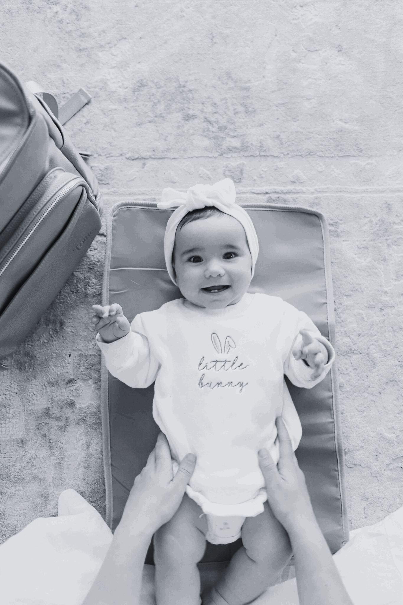 Black and white image of a baby on a Tottie's nappy change mat